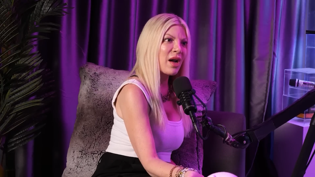 Tori Spelling speaks under beautiful purple lighting.