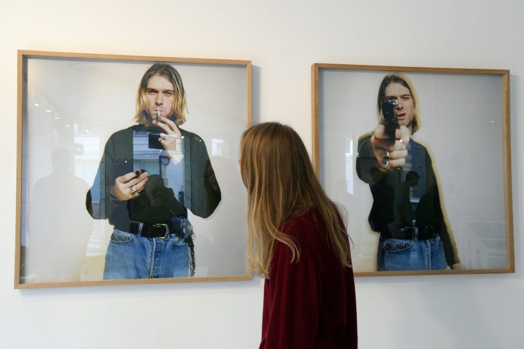 A woman looks at photos of late singer Kurt Cobain, posing with a handgun, as part of the exhibition "The Last Shooting" on March 28, 2014 at the Addict gallery in Paris. 