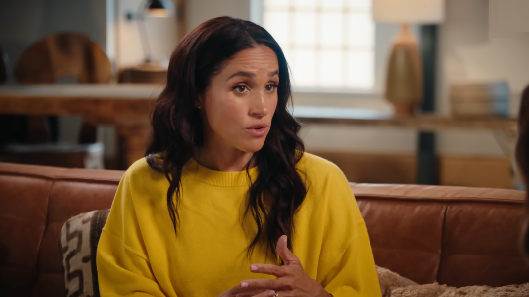 Meghan Markle in a yellow blouse while chatting.
