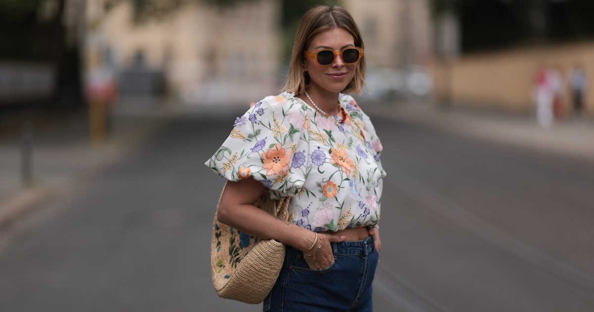 Aline Kaplan wearing Baum & Pferdgarten wide leg blue denim pants, & other stories white flower pattern cropped blouse and orange summer heels and Mango orange black shades on June 06, 2023 in Berlin, Germany.