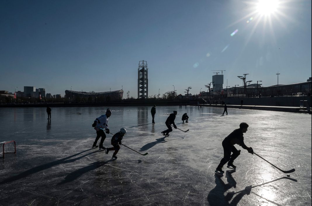 People play hockey on the frozen ice near the National Stadium at Olympic Park on January 13, 2022 in Beijing, China.